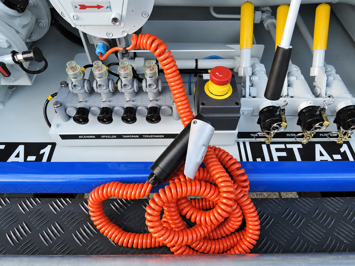 Handheld deadman control with an orange coiled line beside an aircraft fuelling control panel